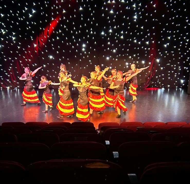 Jazz routine with coordinated arm movements under purple lighting